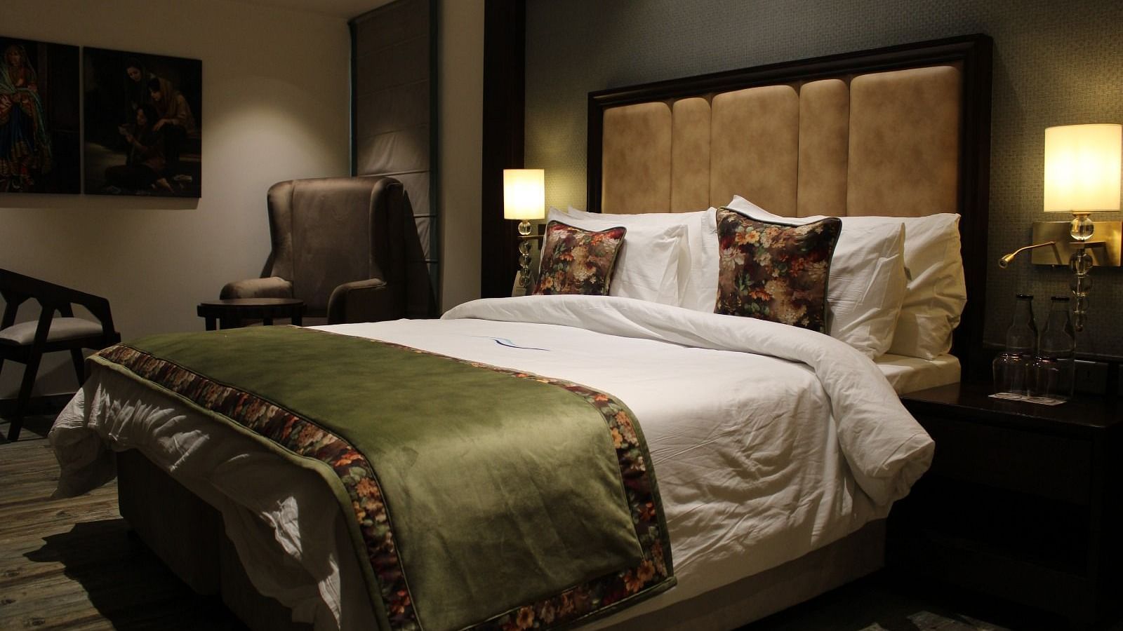 Side view of the bedroom with multiple pillows arranged on the bed and a huge chair next to it at BluSalzz Residence, Amritsar